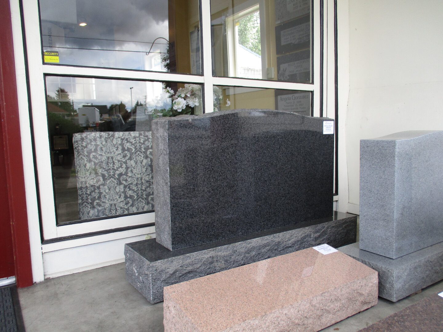 A black granite tombstone in front of a window