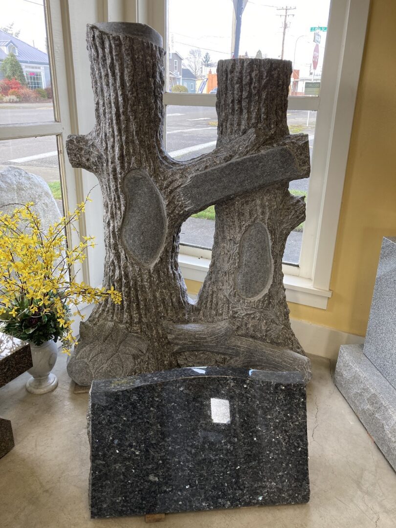 A back tombstone in front of two tree trunks