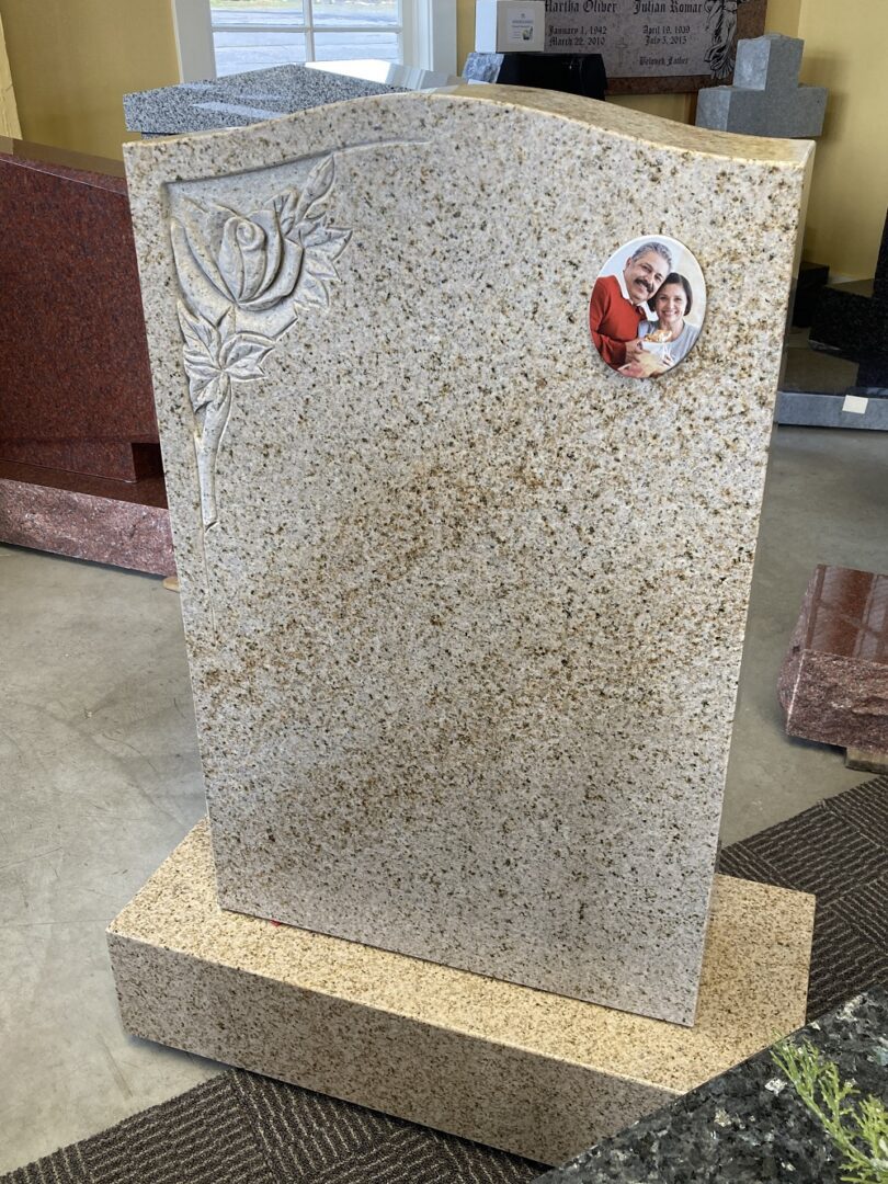 A tombstone with engraved flower and an oval cut of a couple’s picture